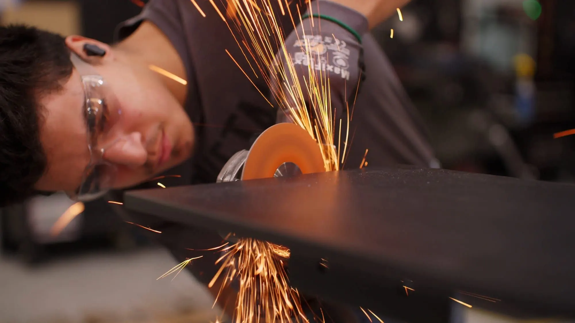 Dovetail metal fabricator grinding a steel edge