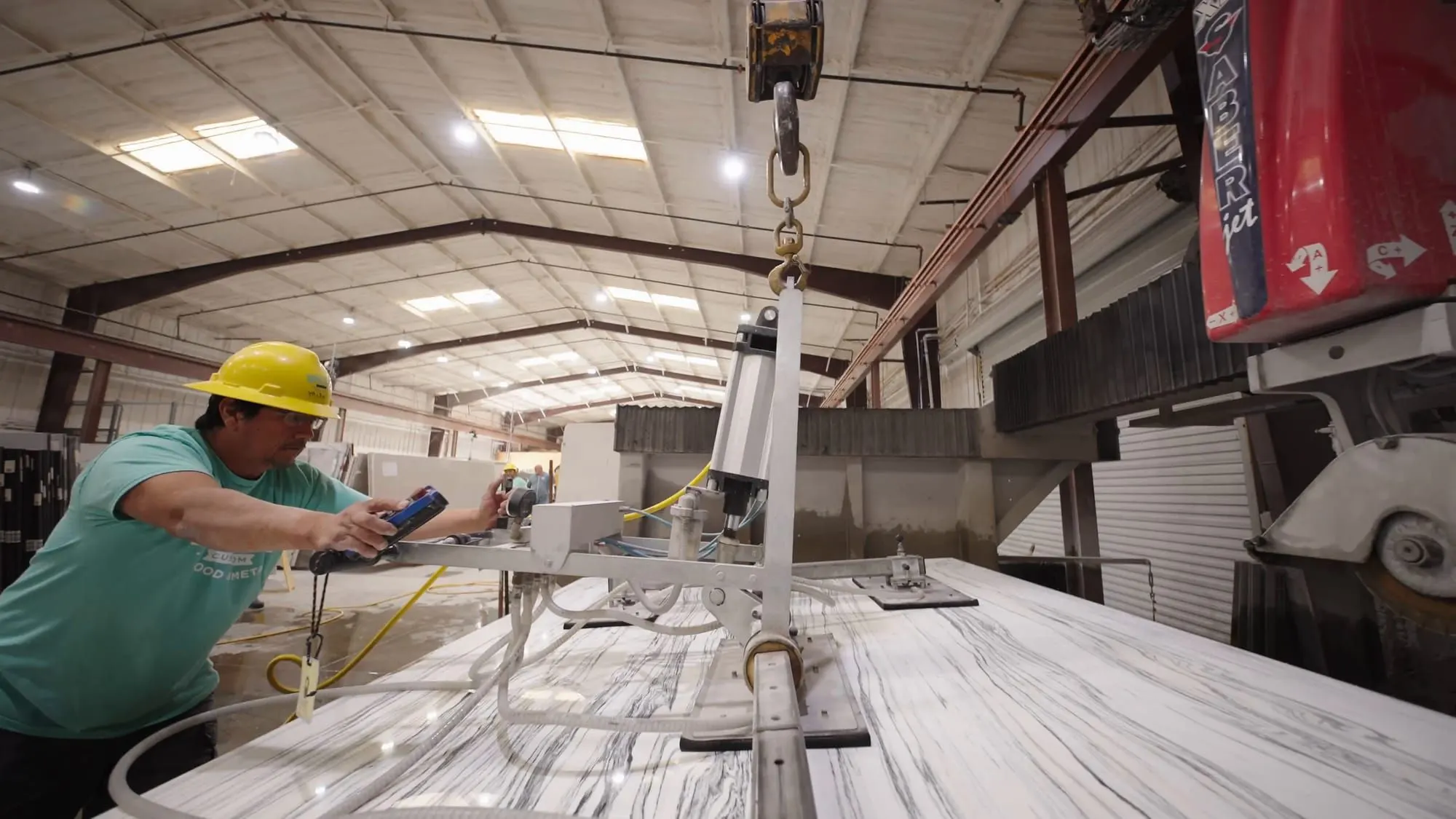 Dovetail stone fabricator guiding a marble slab on the lift