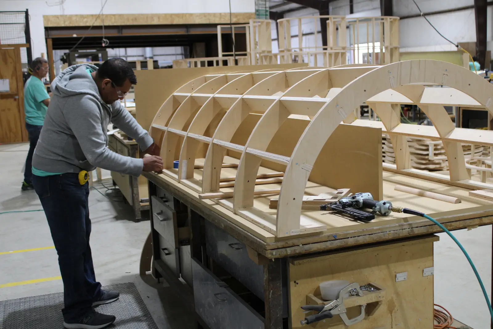 Dovetail craftsman assembling a curved wood rib panel in the shop