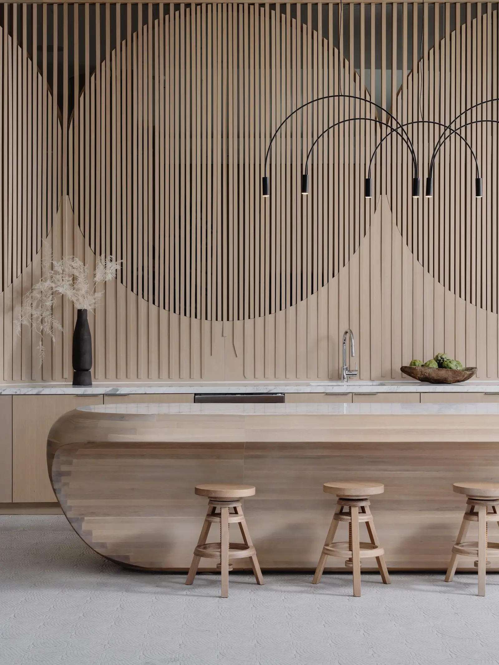 44 East sculpted wood island with a stone top below a slatted wood wall with a circle pattern