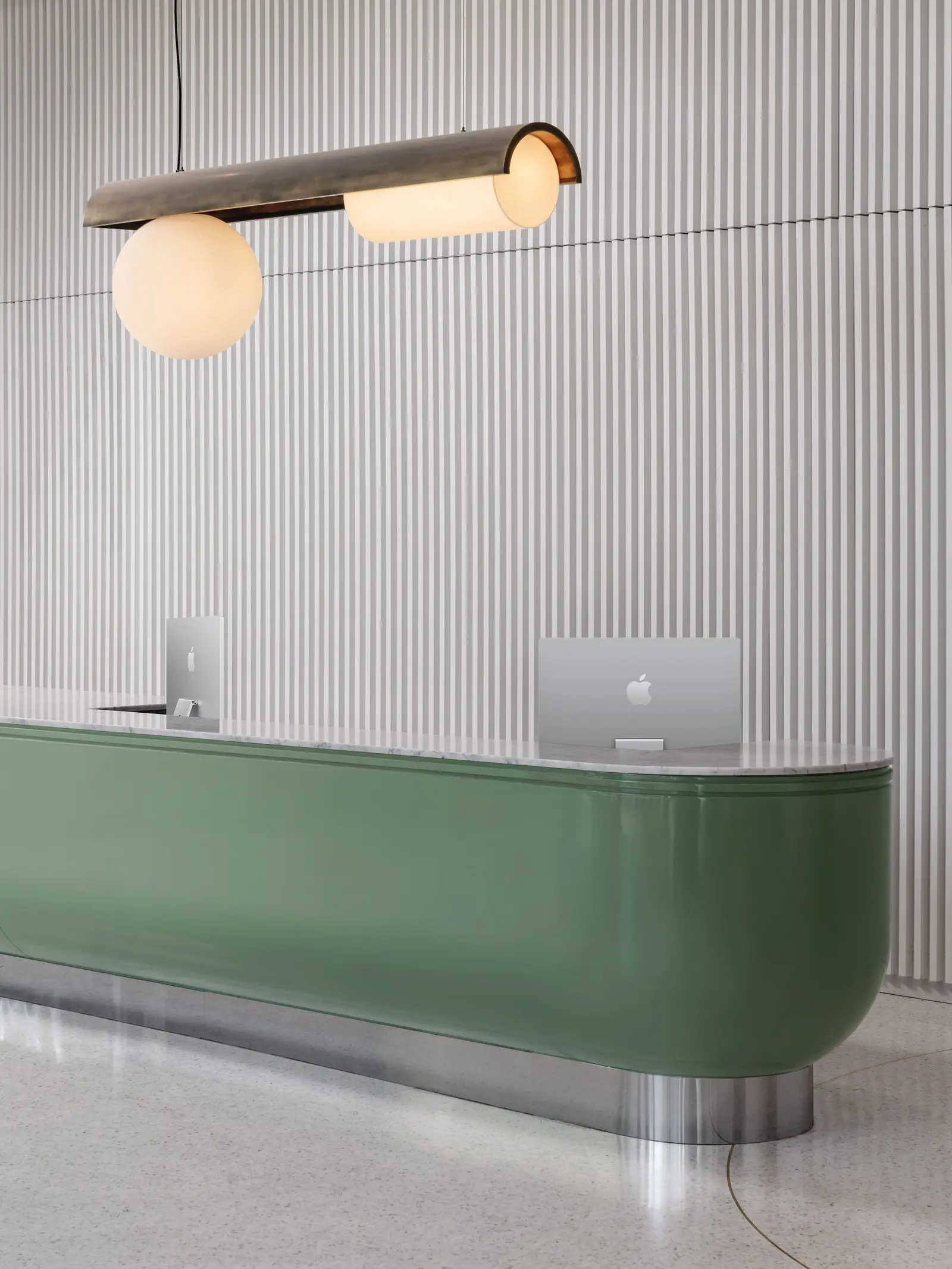 44 East green reception counter in front of a fluted wall with a brass pendant