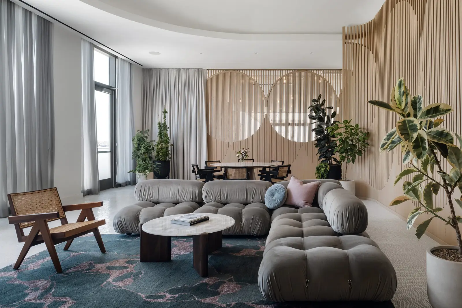 44 East lounge with a tufted gray sectional and a wood slat wall with round cutouts