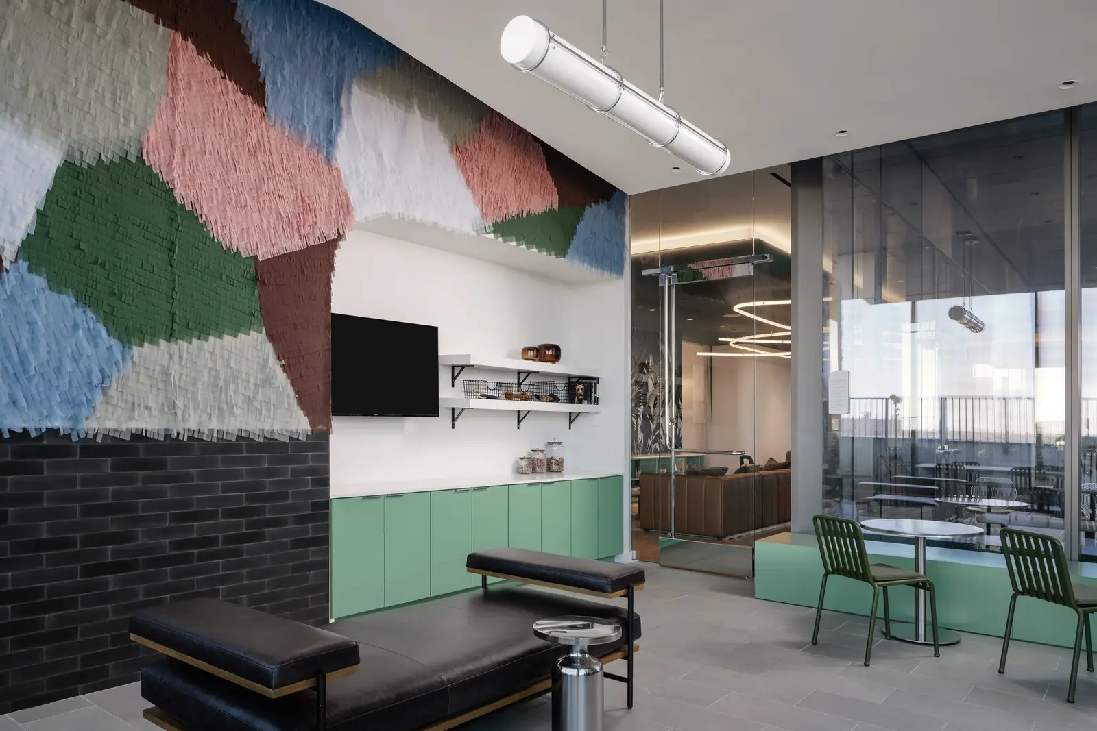 44 East lounge with a colorful tufted wall, black leather seating and a TV
