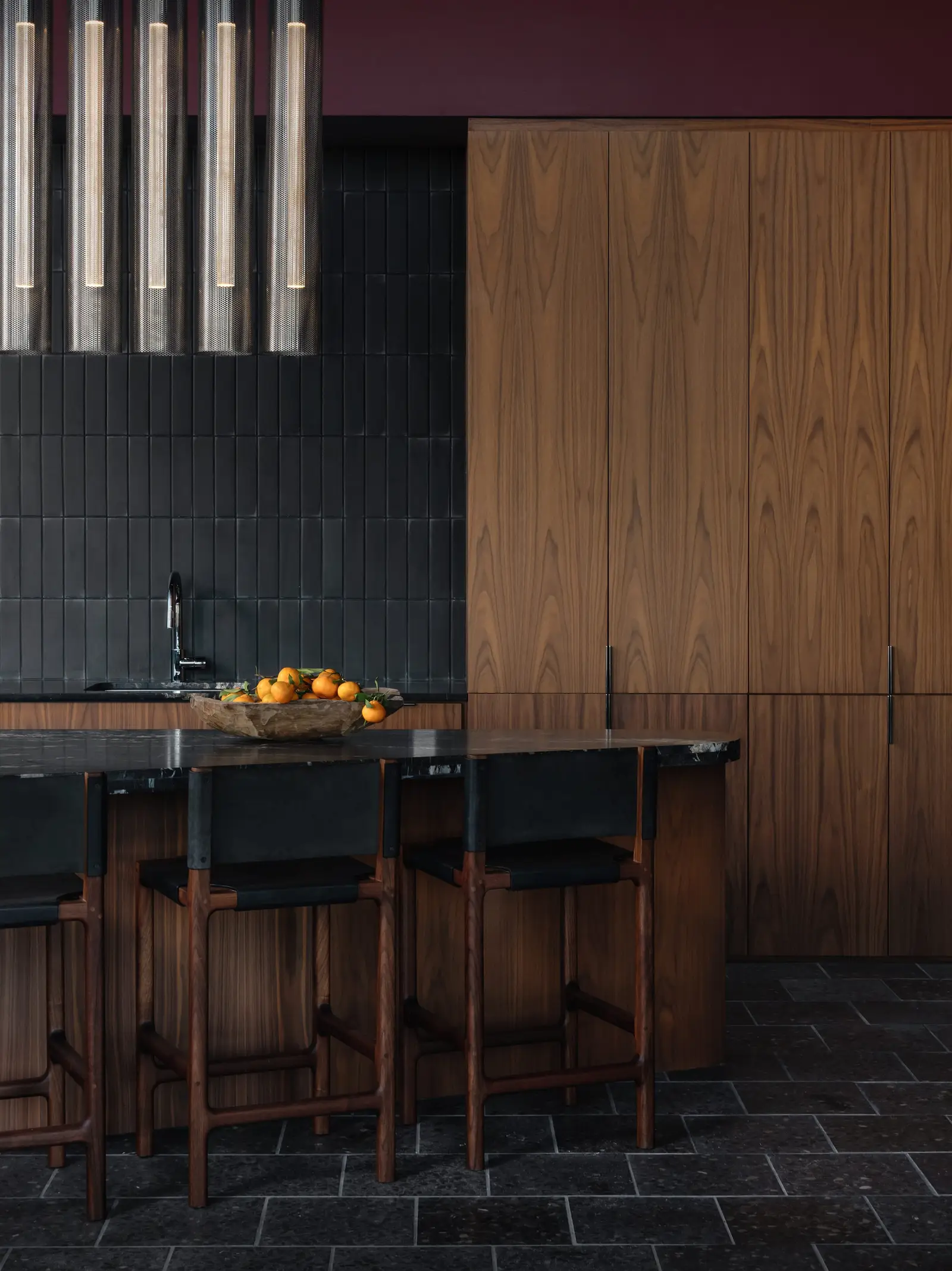 44 East kitchen bar with wood cabinets, dark tile and stools