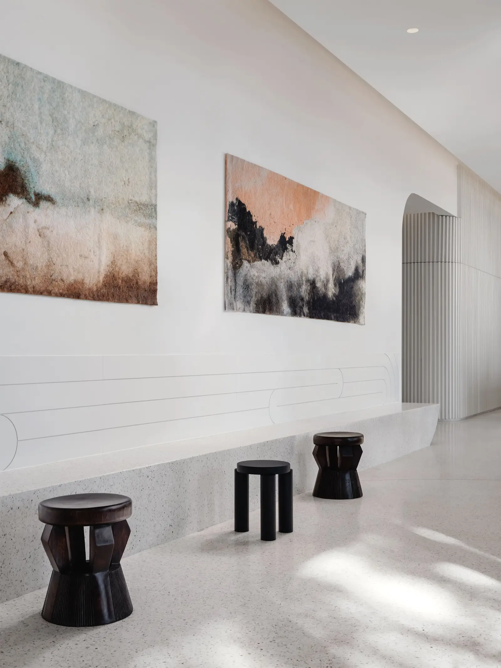 44 East hallway with a stone-look bench, black stools and two paintings