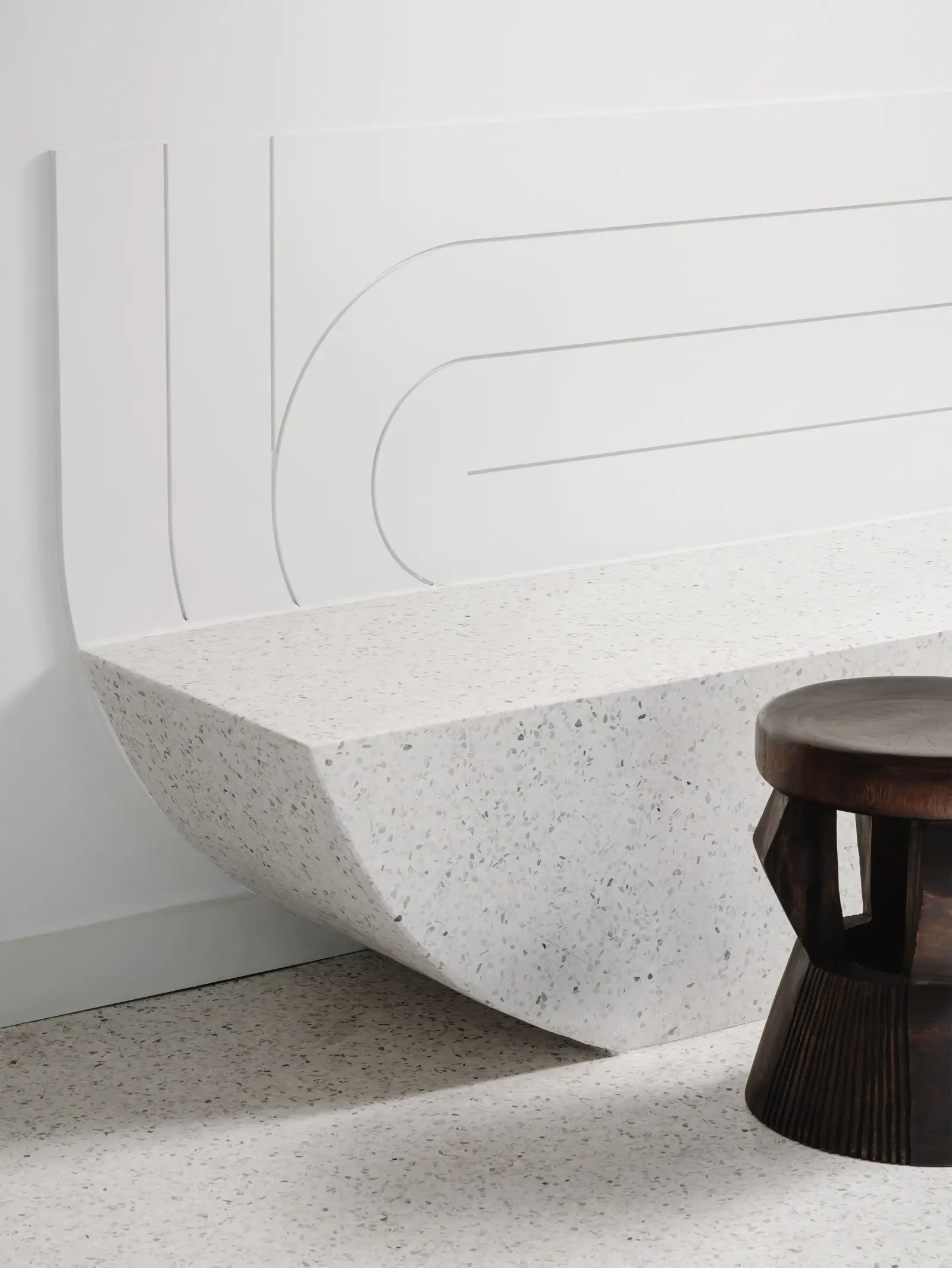 44 East curved stone bench built against a white wall with a carved line detail