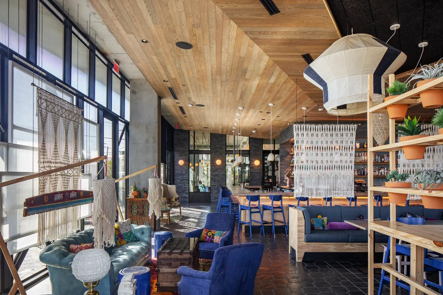 Arrive Hotel hotel lounge with a wood ceiling, blue chairs and shelving