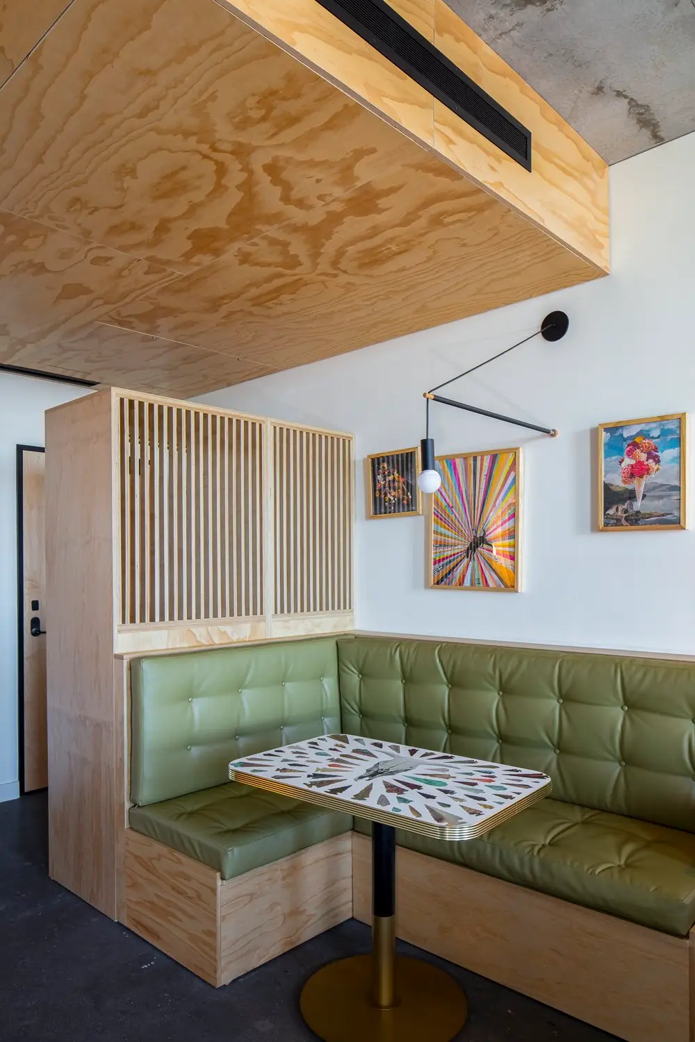 Arrive Hotel corner booth with green tufted seating under a wood ceiling