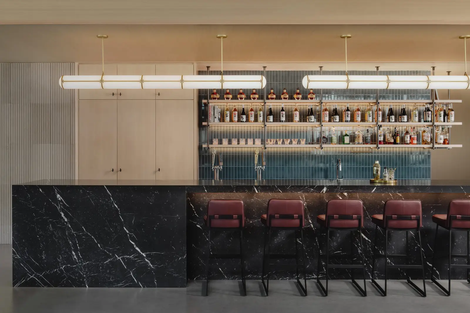Atmosphere TV bar with a black stone-front counter, red stools and lit back-bar shelves