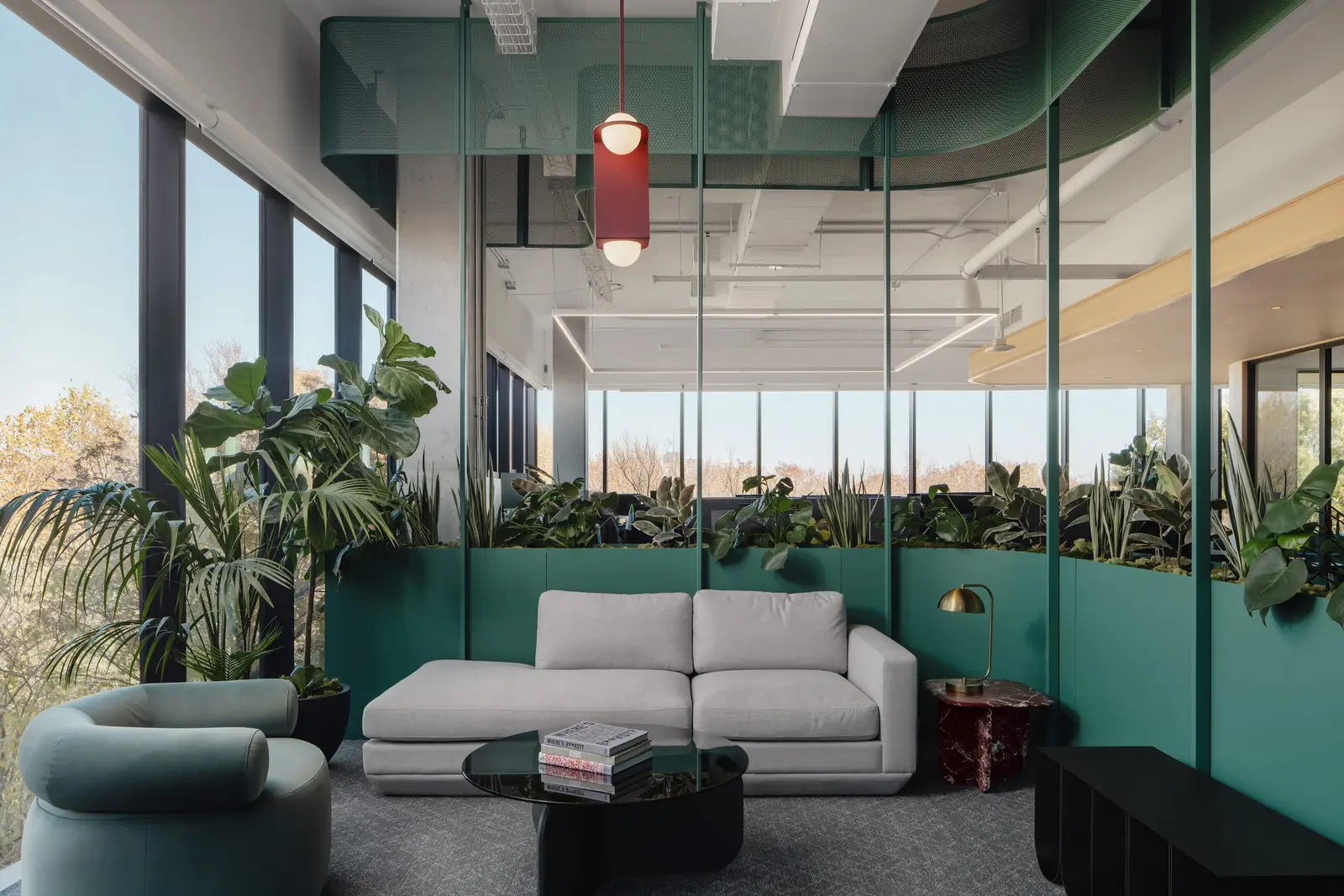 Atmosphere TV glass-walled lounge with a gray sofa and a green planter wall
