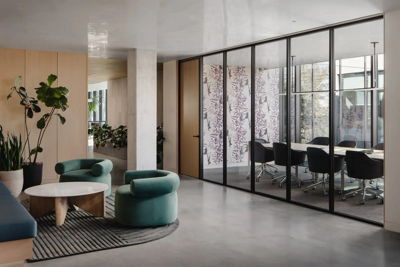 Atmosphere TV meeting room behind black-framed glass and a lounge nook with green chairs