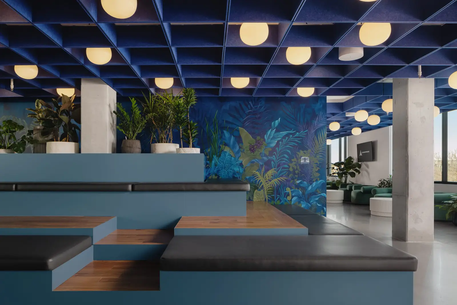 Atmosphere TV tiered seating with wood and black steps under a blue grid ceiling