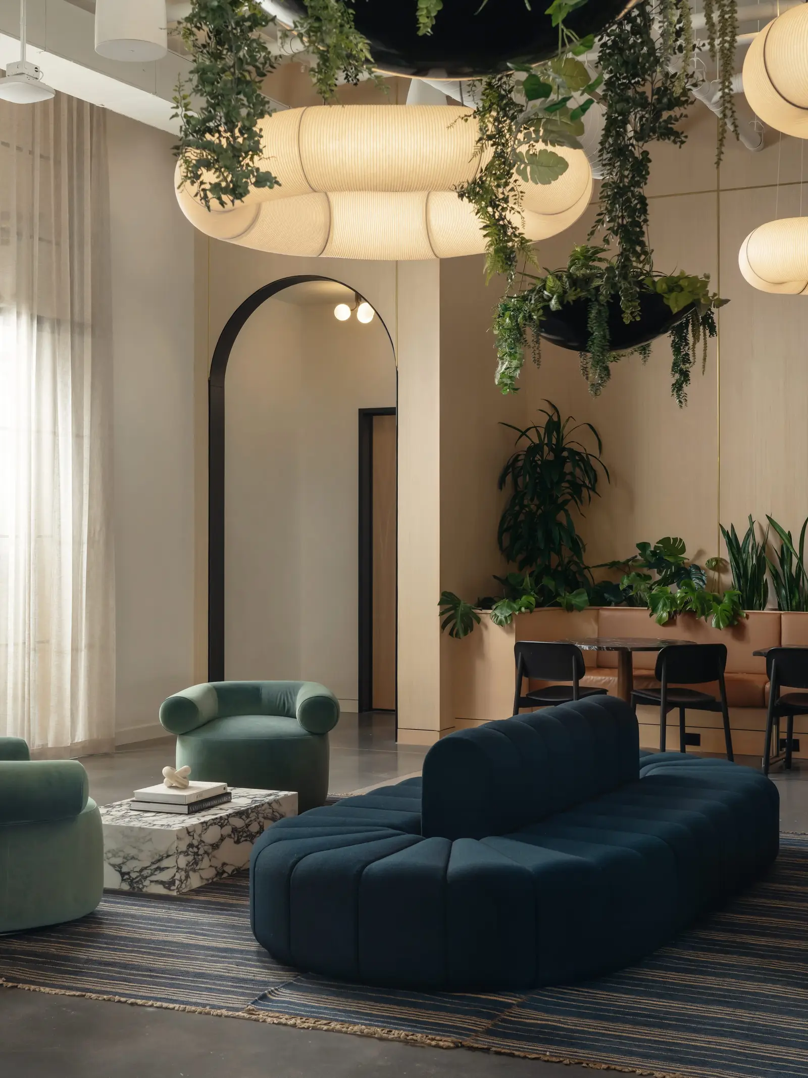 Atmosphere TV lounge with a blue sofa, round pendant lights and hanging plants