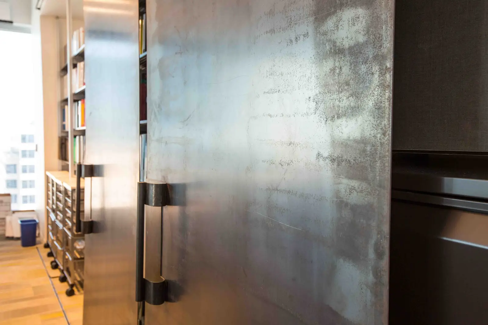 Boka Powell metal-finished sliding door partly open beside bookshelves