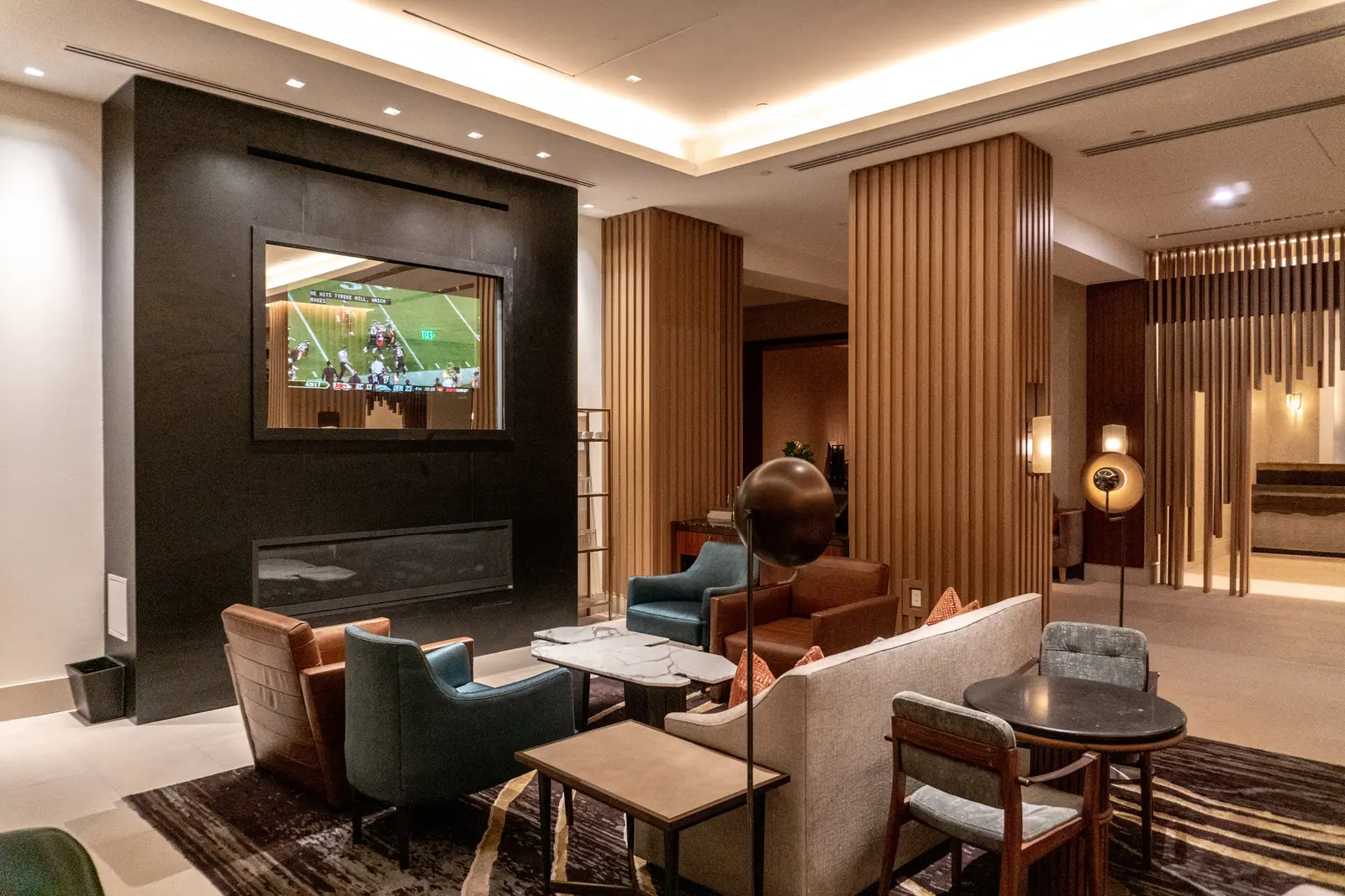 Four Seasons Hotel lounge with a TV above a fireplace wall, wood columns and seating