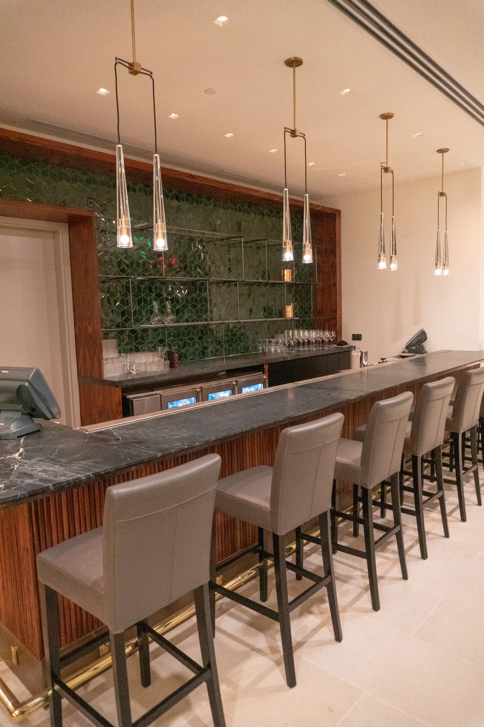 Four Seasons Hotel bar with a stone top, tall stools and a green wall
