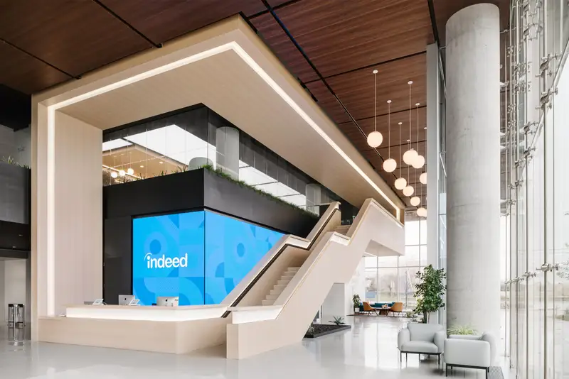 Indeed lobby with a glowing wood-framed reception and stair
