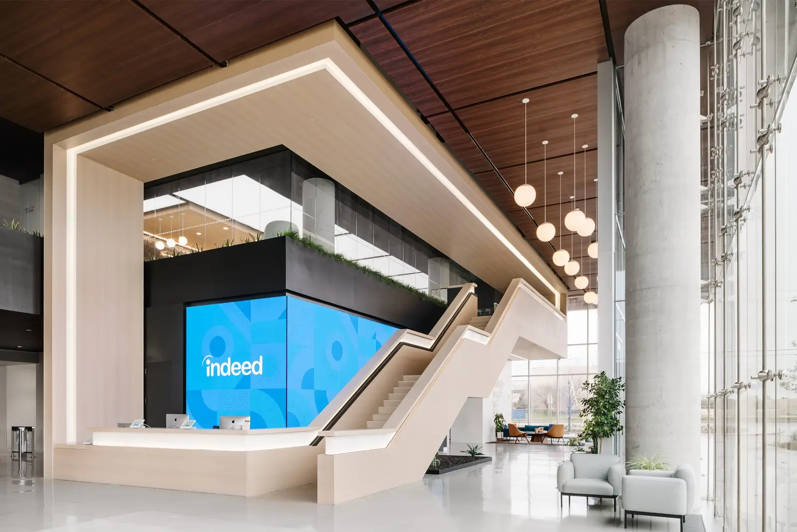 Indeed lobby with a glowing wood-framed reception and stair