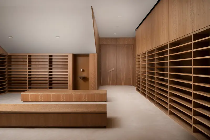 Ismaili Centre library room with a wood wall of open slotted shelving and a low wood bench