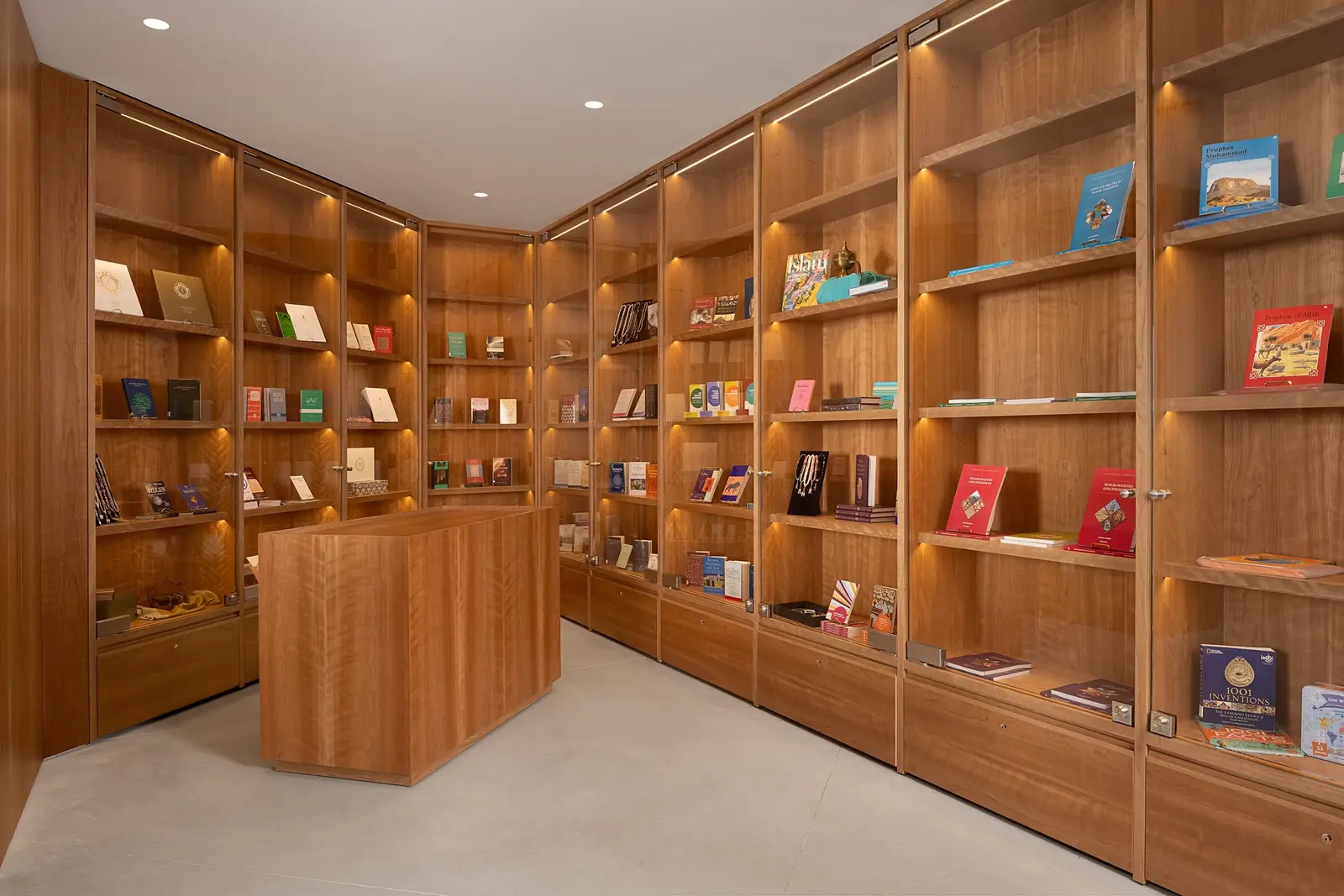 Ismaili Centre corner display room with lit wood bookshelves and a wood display counter