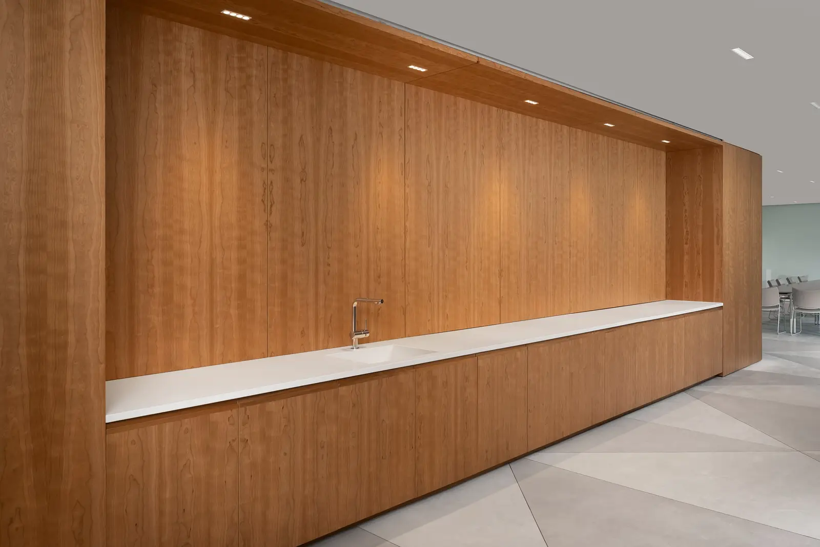 Ismaili Centre long wood wall with an integrated white-top counter and downlights