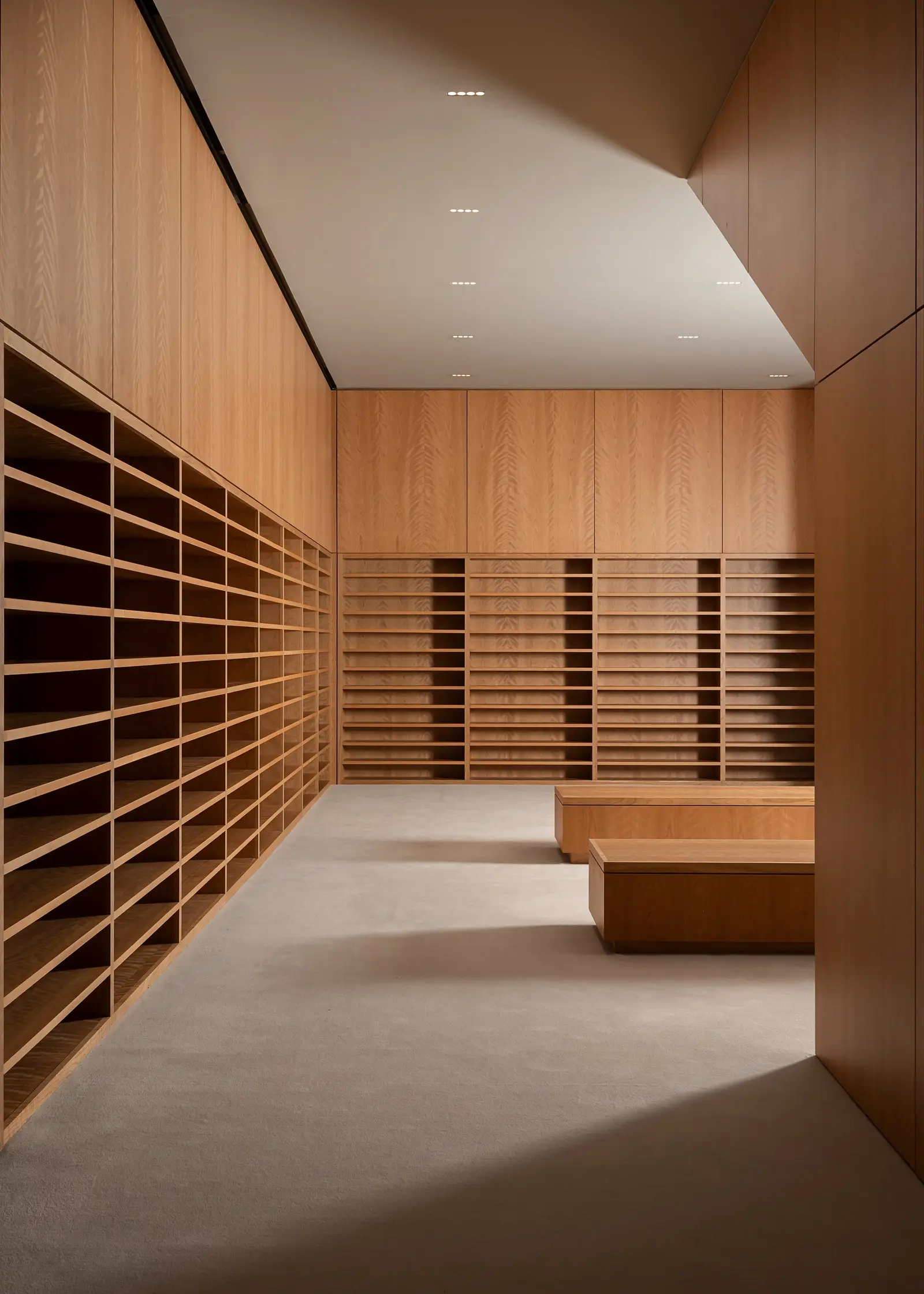Ismaili Centre wood wall with slotted cubby shelving and a bench