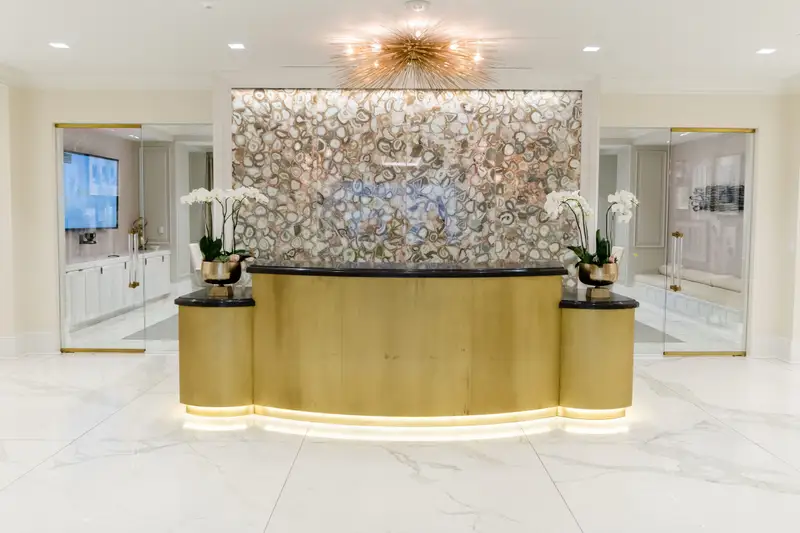 Kendra Scott reception desk with a gold-tone front and a mosaic wall