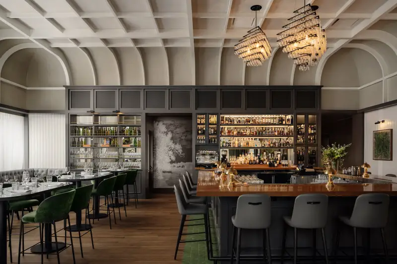 The Kitchen Bistro restaurant bar with a vaulted ceiling, back-bar shelving and chandeliers