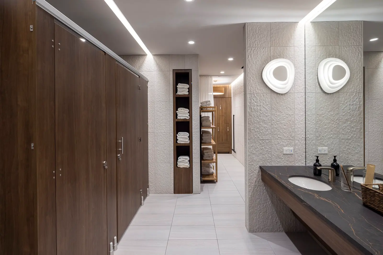 Kuya Wellness locker room with wood stall doors, a dark vanity and a mirror