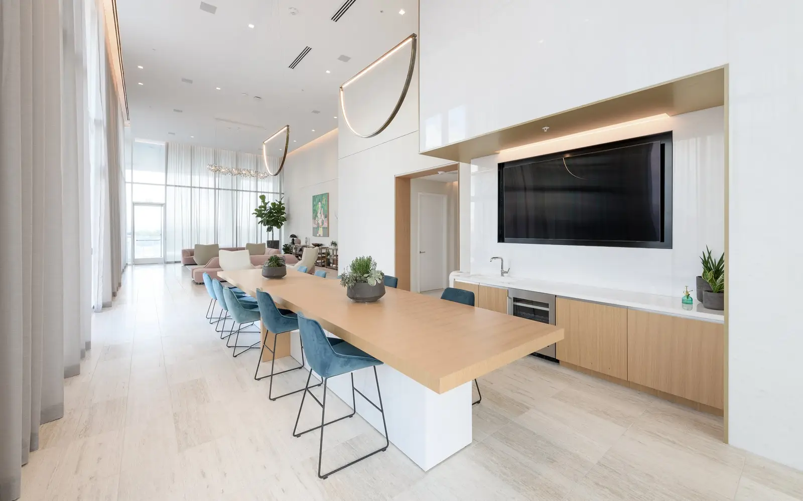 Linden Residences long amenity kitchen with a wood-top table, blue stools and a TV wall