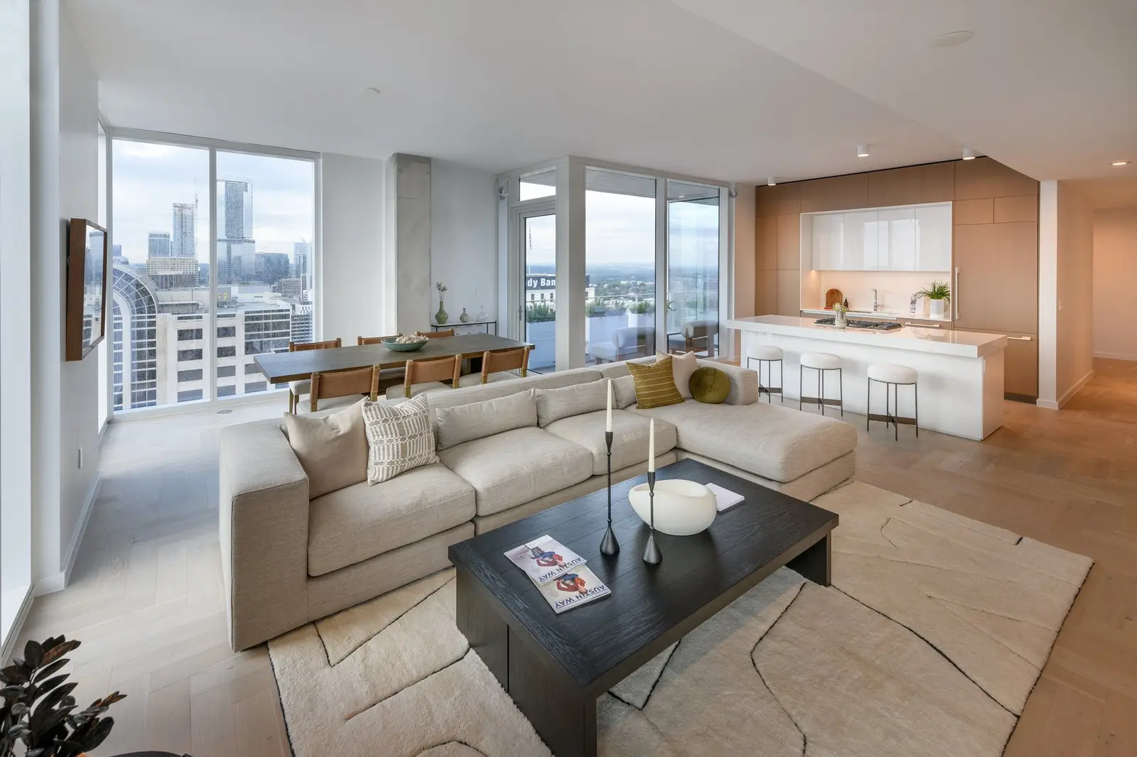 Linden Residences living area with a sectional sofa and open kitchen overlooking the city
