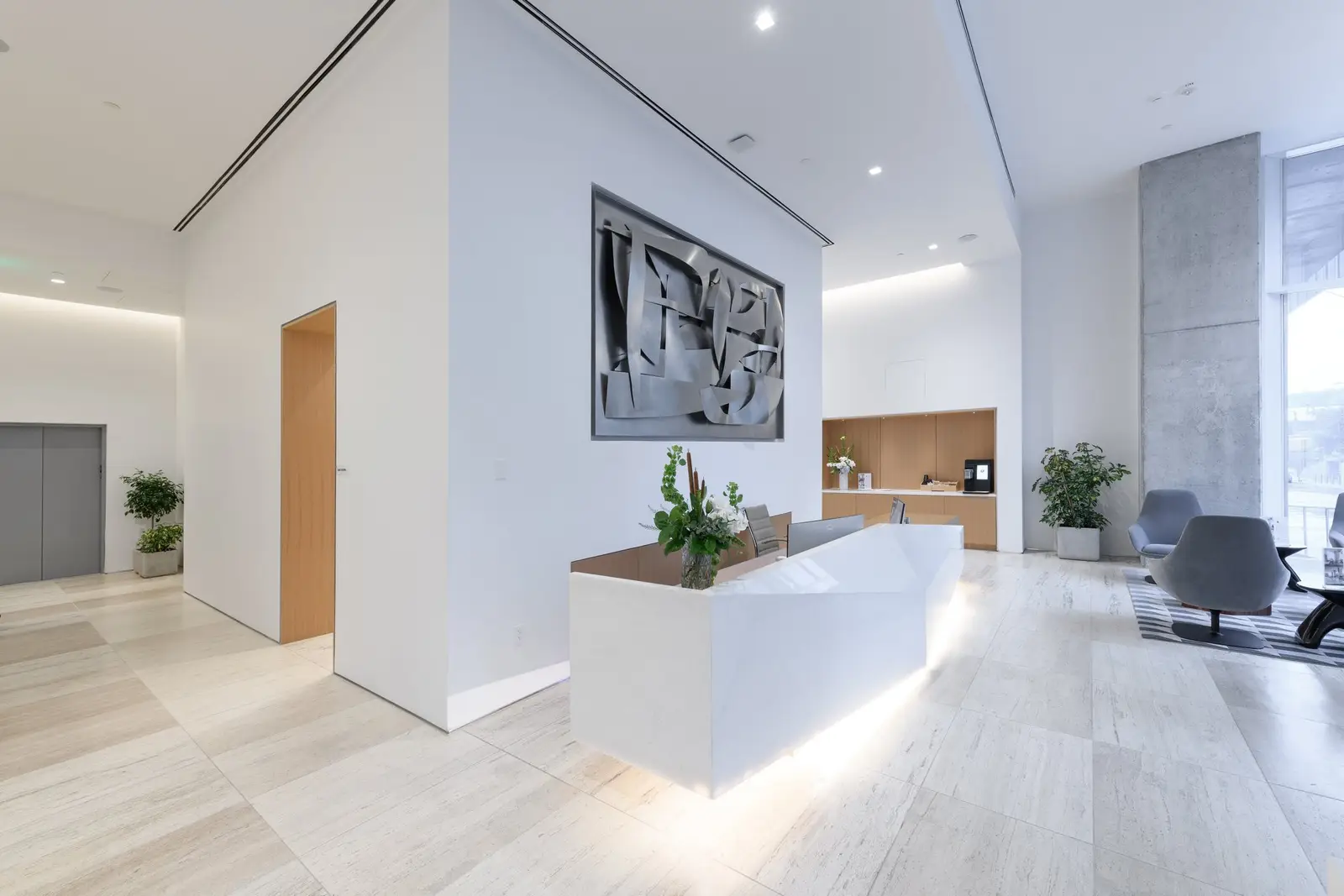 Linden Residences reception area with a white sculpted desk and wall art