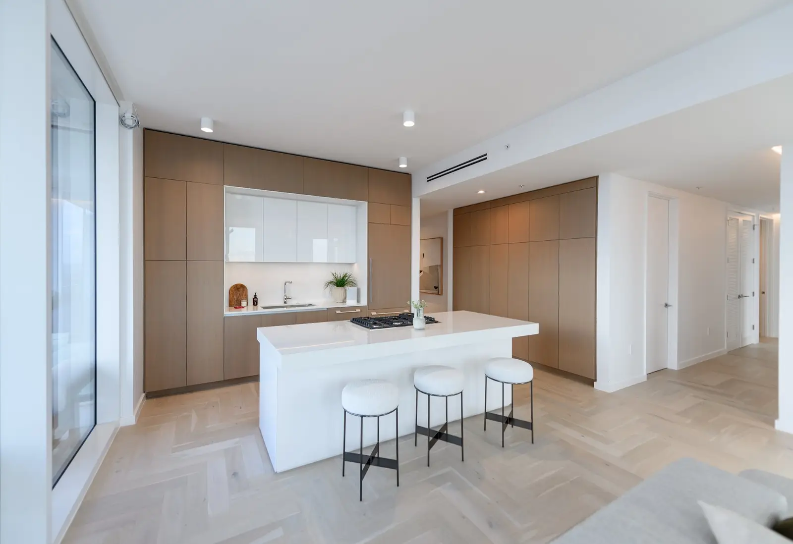 Linden Residences kitchen with wood cabinet walls, a white island and counter stools