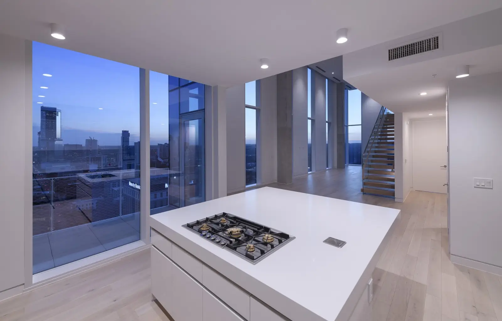 Linden Residences white kitchen island with cooktop and a city view at dusk