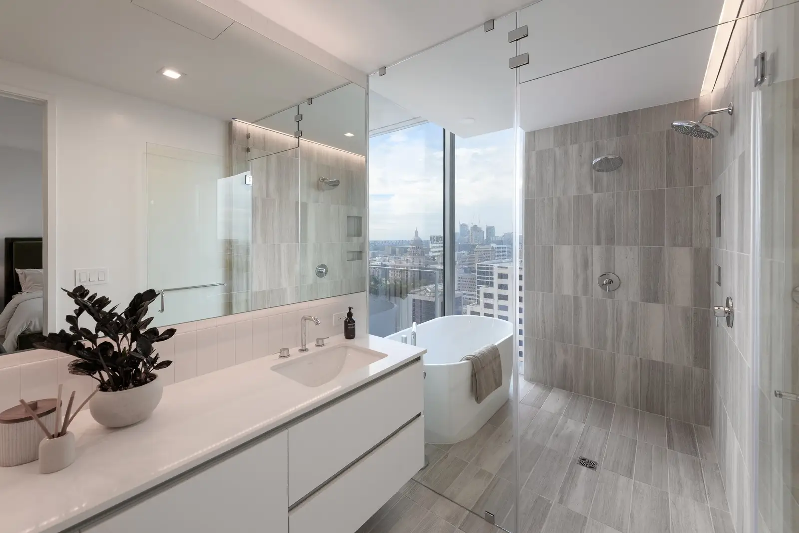 Linden Residences bathroom with a long white vanity, glass shower and soaking tub