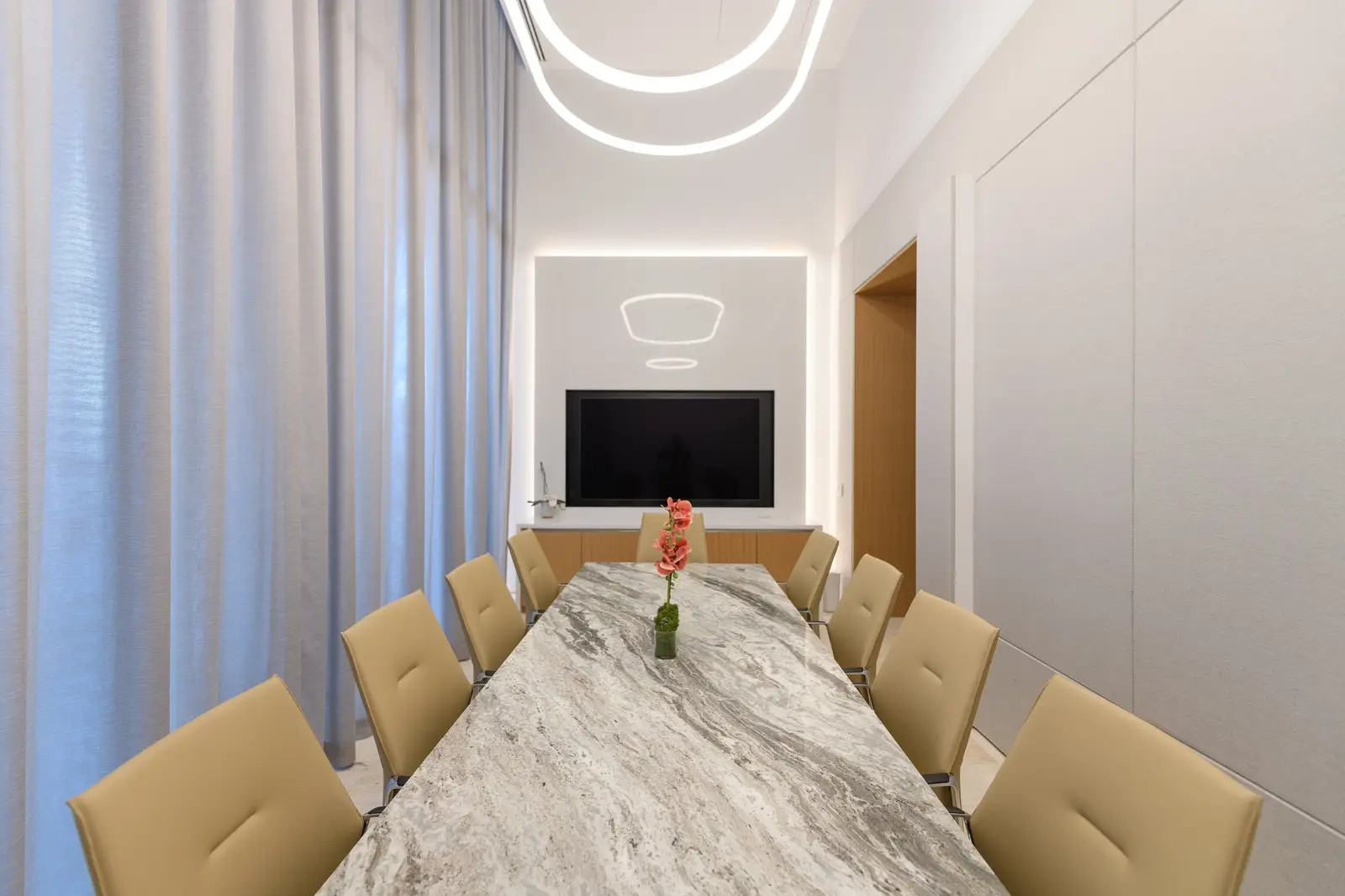 Linden Residences conference room with a stone-topped table, upholstered chairs and a TV wall
