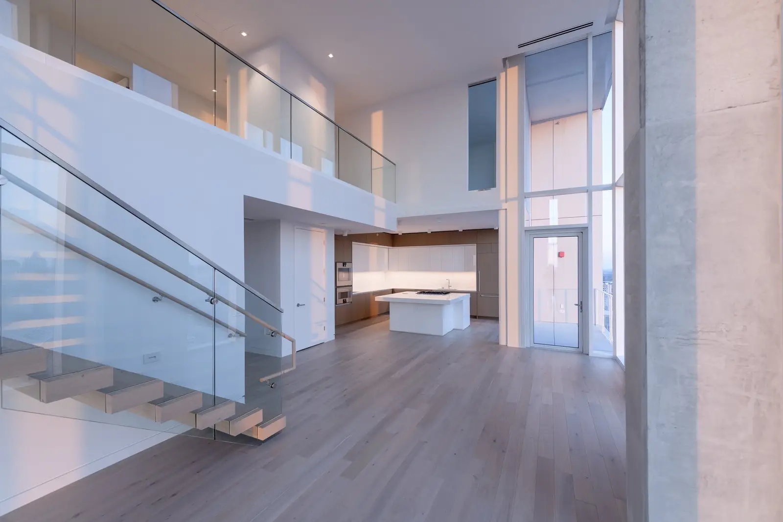 Linden Residences two-story space with a glass stair railing and kitchen beyond