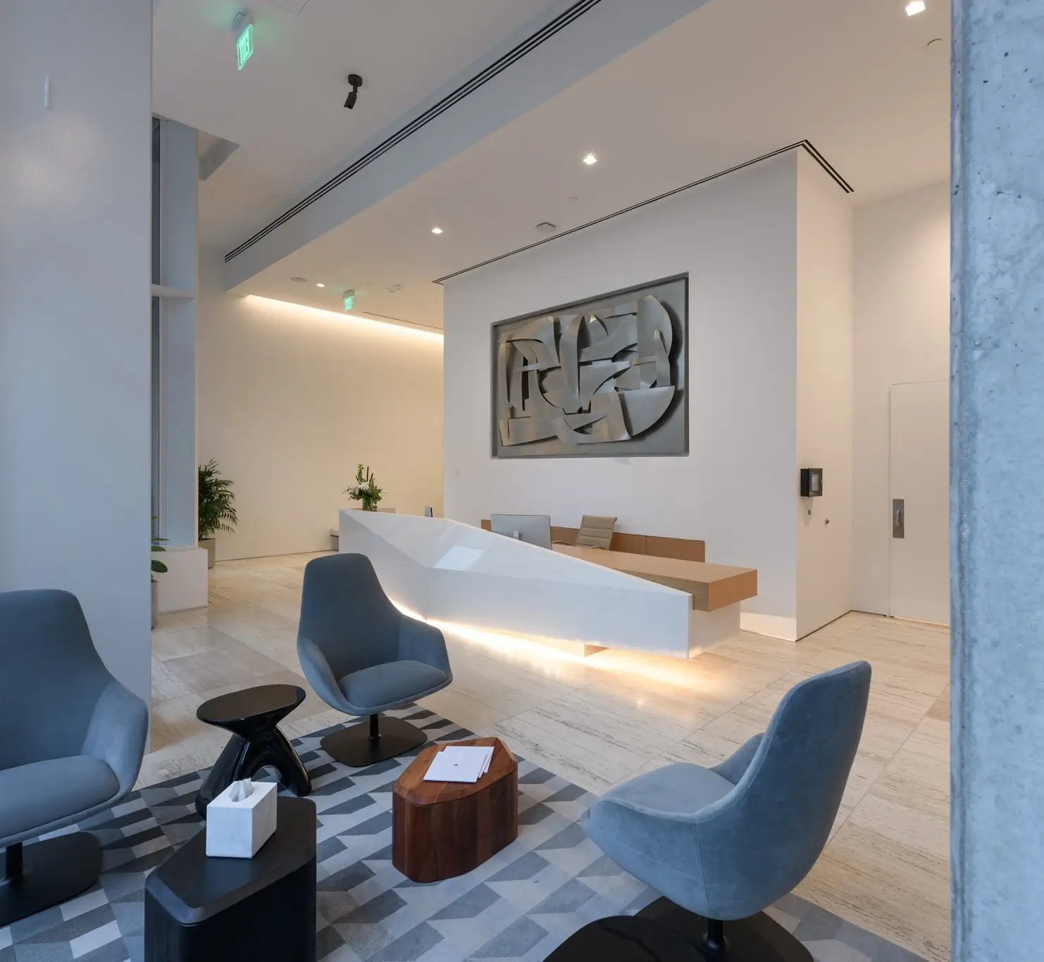 Linden Residences lobby lounge with a white sculpted desk, blue chairs and wall art
