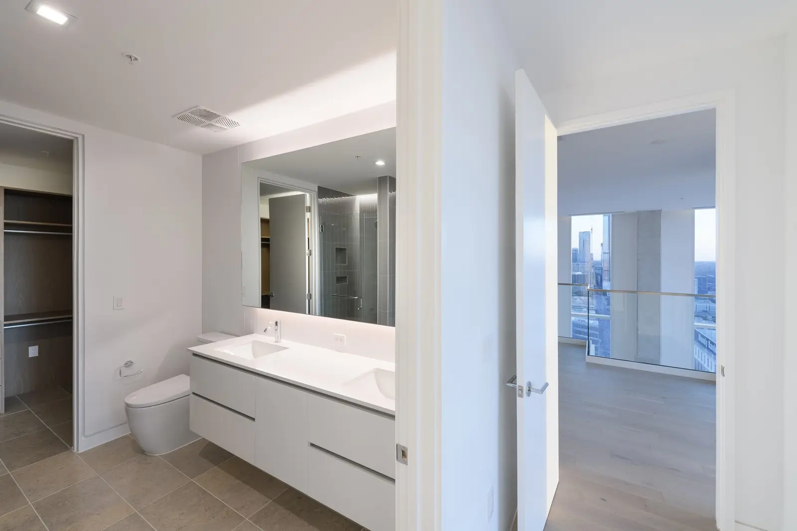 Linden Residences bathroom with a white vanity, mirror and open doorway to a window