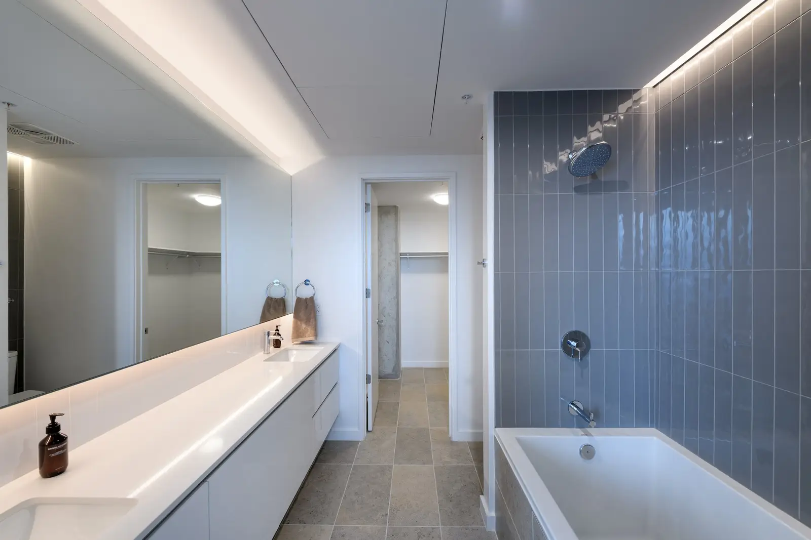 Linden Residences bathroom with blue tile tub surround and a long vanity