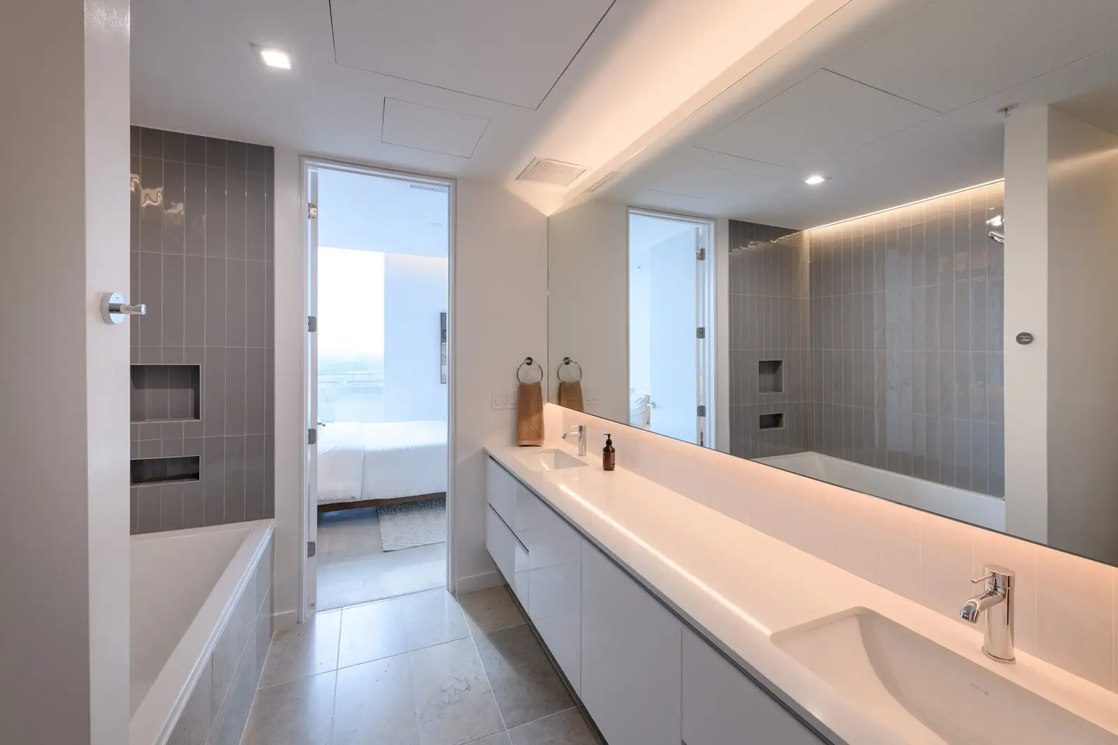 Linden Residences bathroom with a long lit vanity and mirrored wall