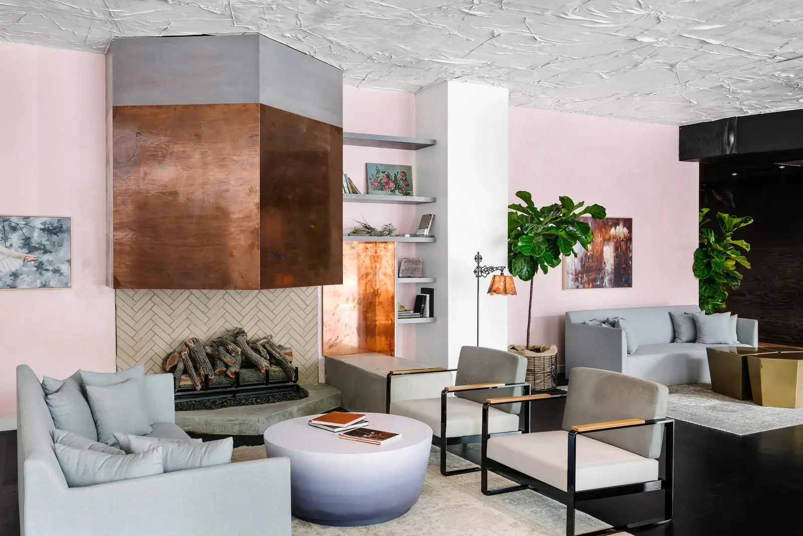 Line Hotel lounge with a copper-clad fireplace hood and pink walls