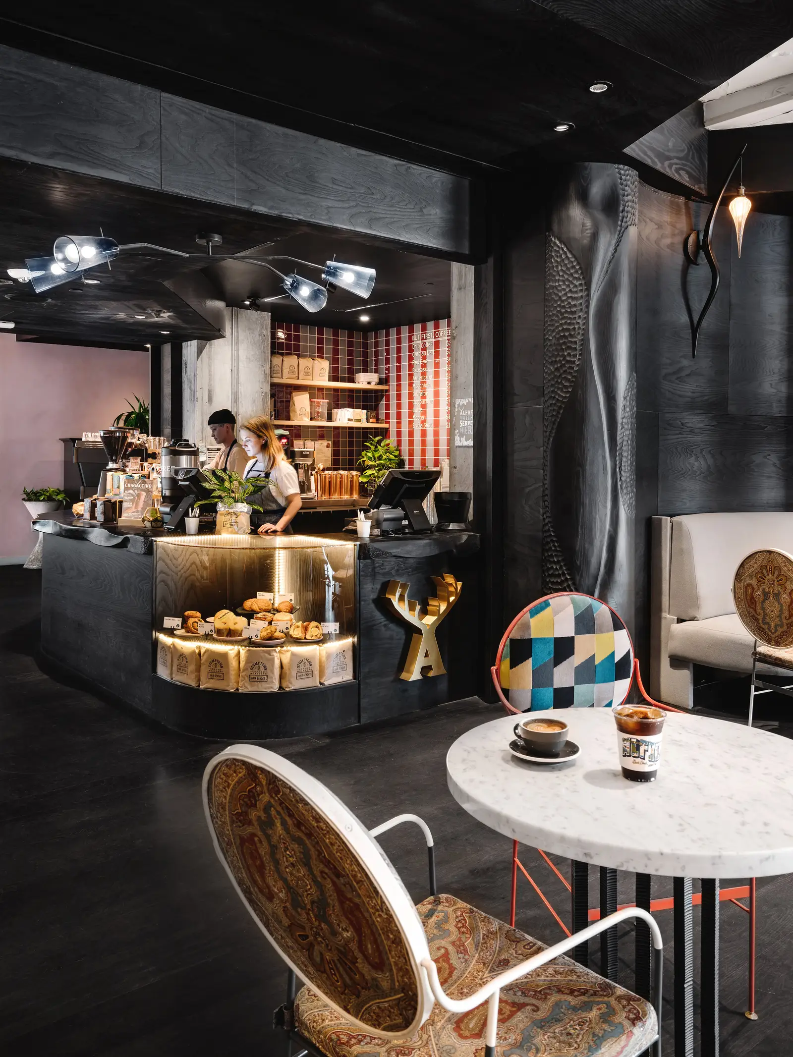 Line Hotel cafe counter with pastries in a dark room with a patterned wall