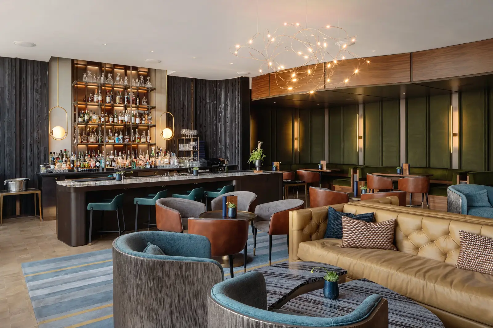 Loren Hotel hotel bar with lit back-bar shelving, a leather banquette and lounge chairs