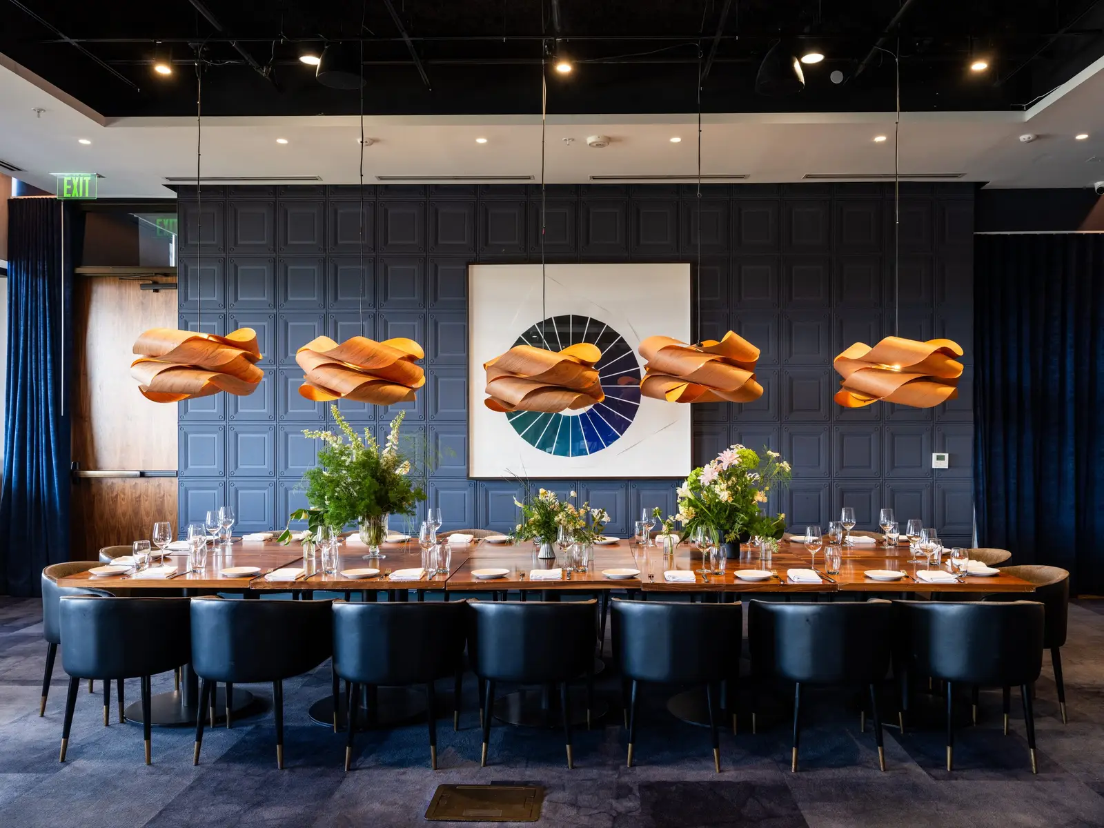 Loren Hotel private dining room with a long table, blue wall panels and orange pendant lights
