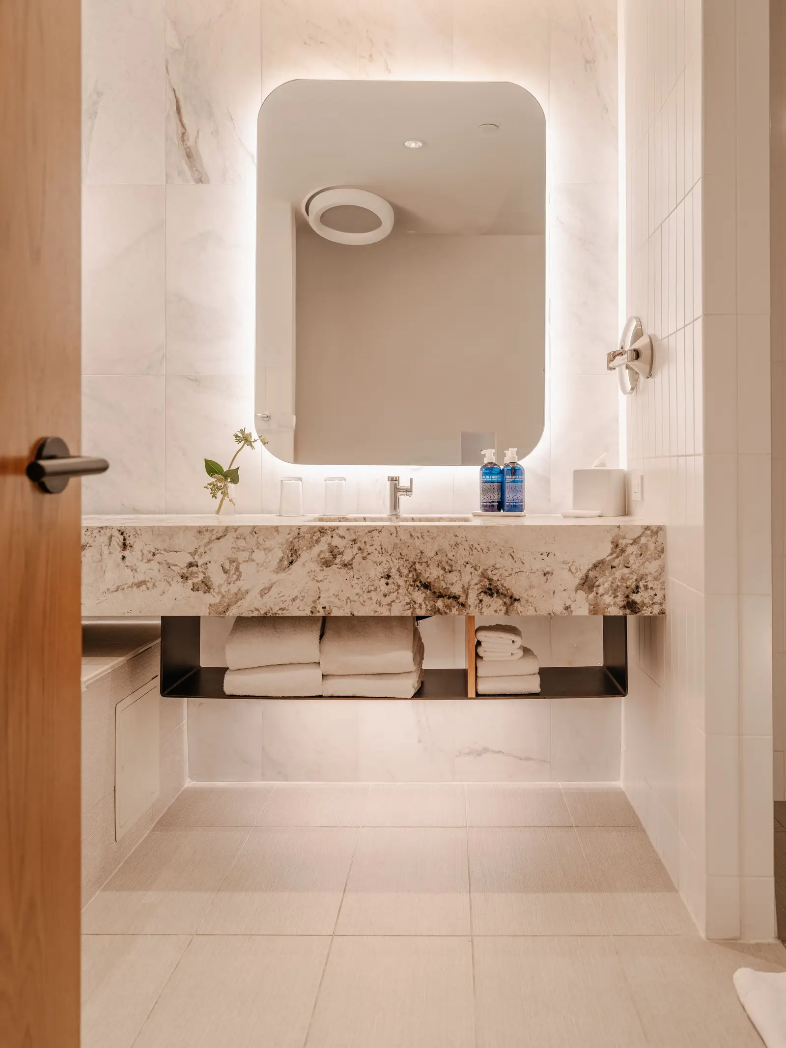 Loren Hotel bathroom with a stone-top vanity and a backlit mirror