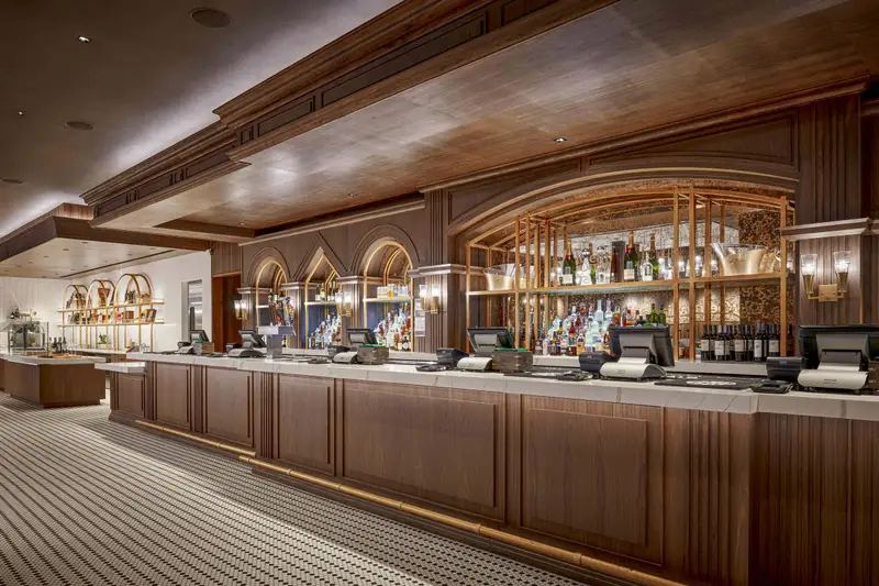 Moody Center club bar with a wood-front counter, arched back-bar shelves and a wood ceiling