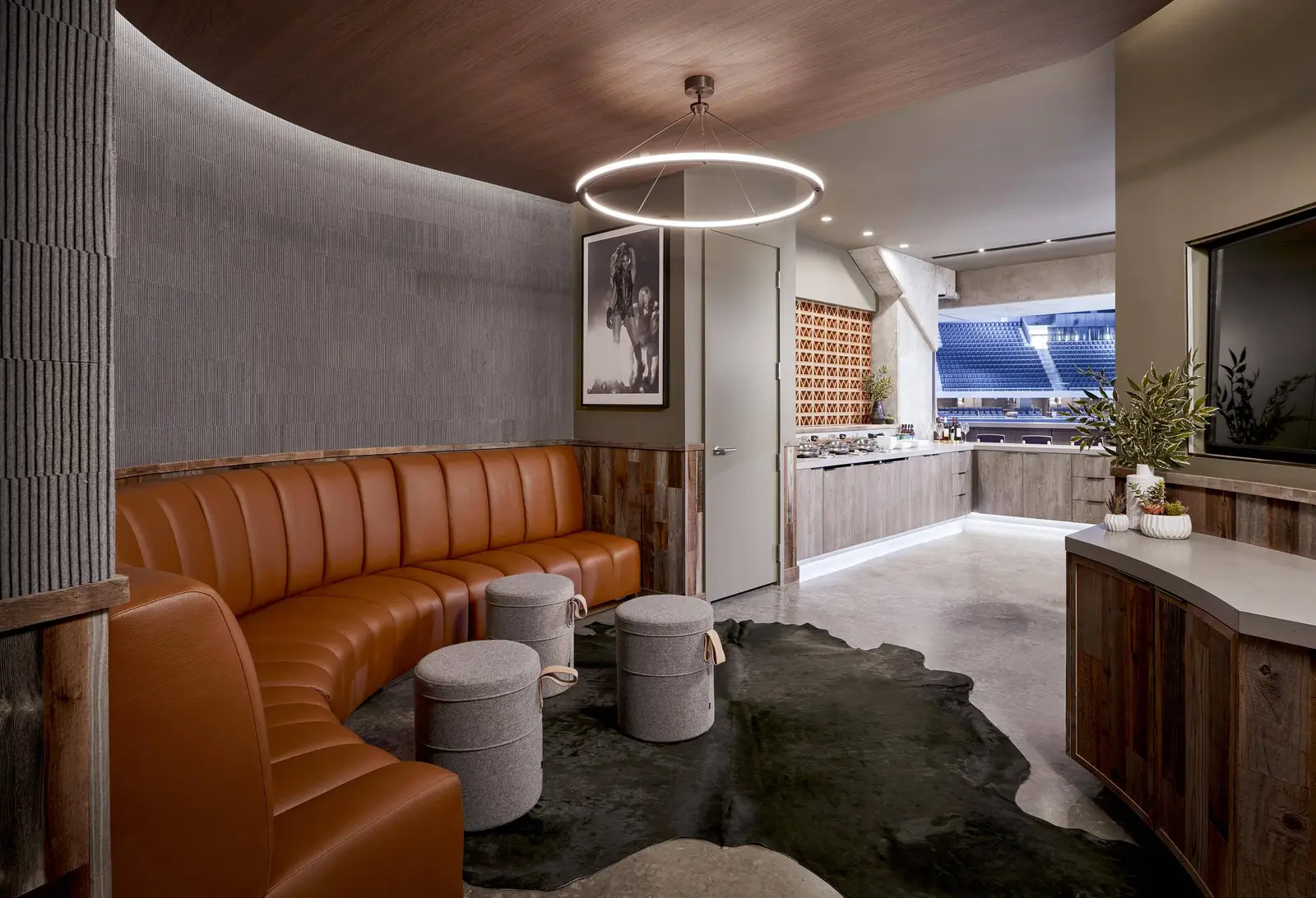 Moody Center suite lounge with a curved leather banquette and a round ceiling light