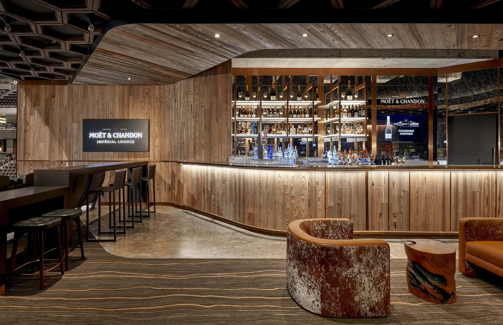 Moody Center bar with a reclaimed wood front, lit shelves and leather chairs