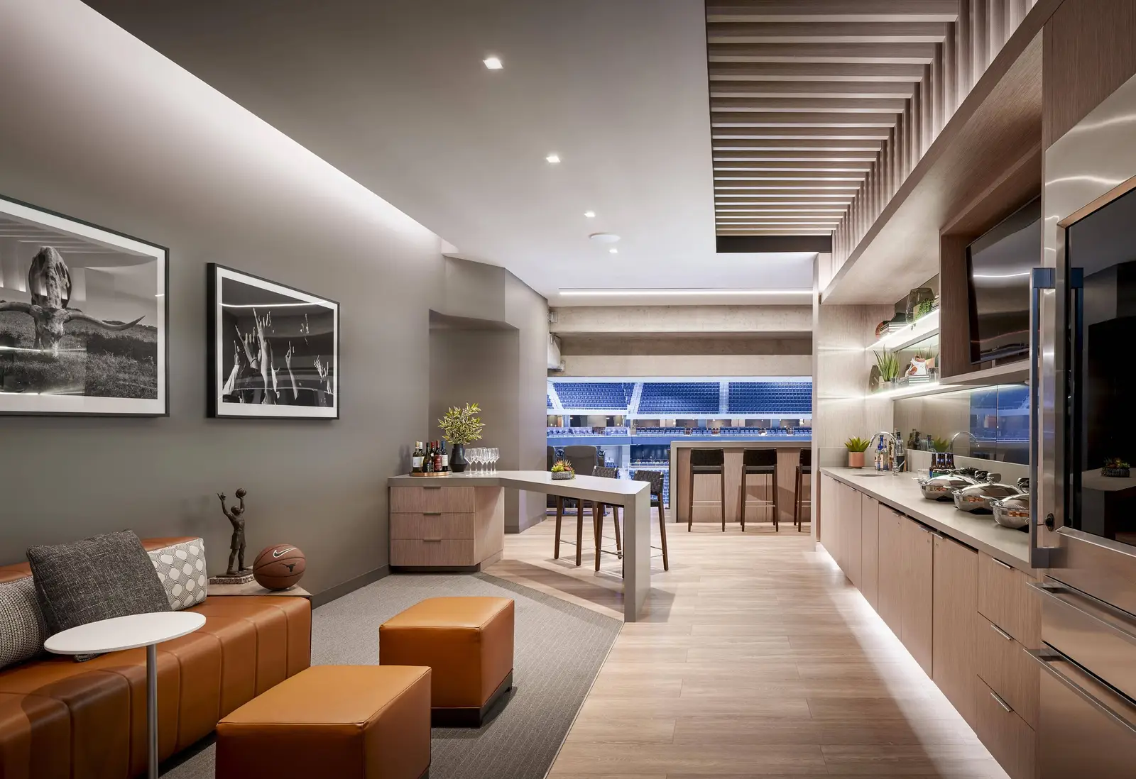 Moody Center suite with leather seating, framed photos and a kitchenette